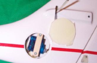 This photo shows the plywood strap in place and the servo fully installed. The little section of antenna wire extending out the hole has been routed in the fin. 