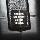 The transmitter charging jack is behind this sticker. the stickers warn not to use with Alkaline batteries.