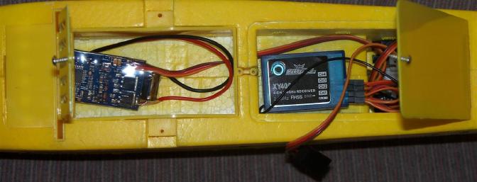 The open battery and receiver access hatches show the loose-fitting ESC and receiver.  The elevator and aileron servos are visible to the right of the receiver.  Note the tiny little retainer tab on the battery hatch which wound up breaking off despite careful handling.